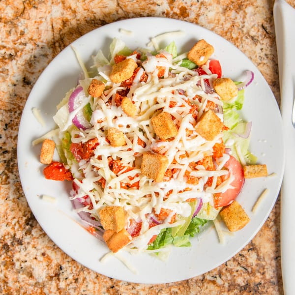 Mama Mia's Pizzeria house salad with lettuce, tomatoes, onions, cheese, croutons, and dressing.