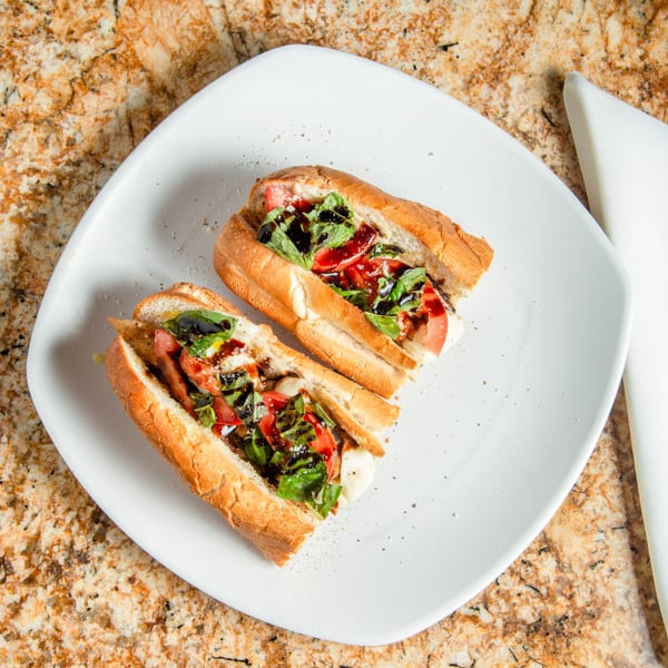 Two Mama Mia's Pizzeria caprese subs with fresh mozzarella, tomatoes, basil, and balsamic glaze.