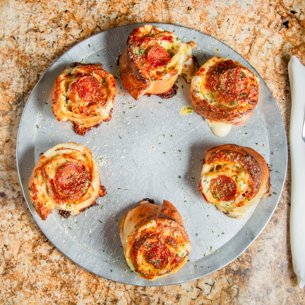 Six Mama Mia's Pizzeria pepperoni pizza rolls with melted cheese and herbs on a metal tray.